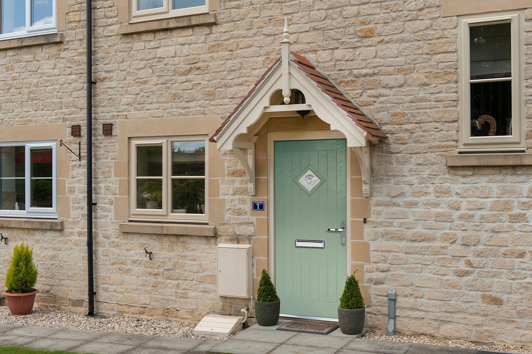 Sage-green composite front door on a stone cottage