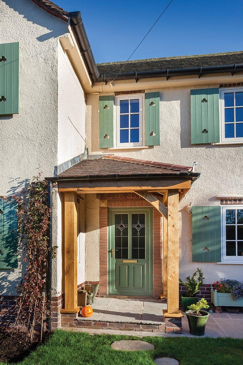 Green composite front door in a timber porch