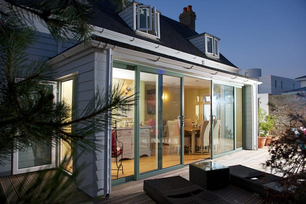 Glazed garden extension lit from inside at dusk