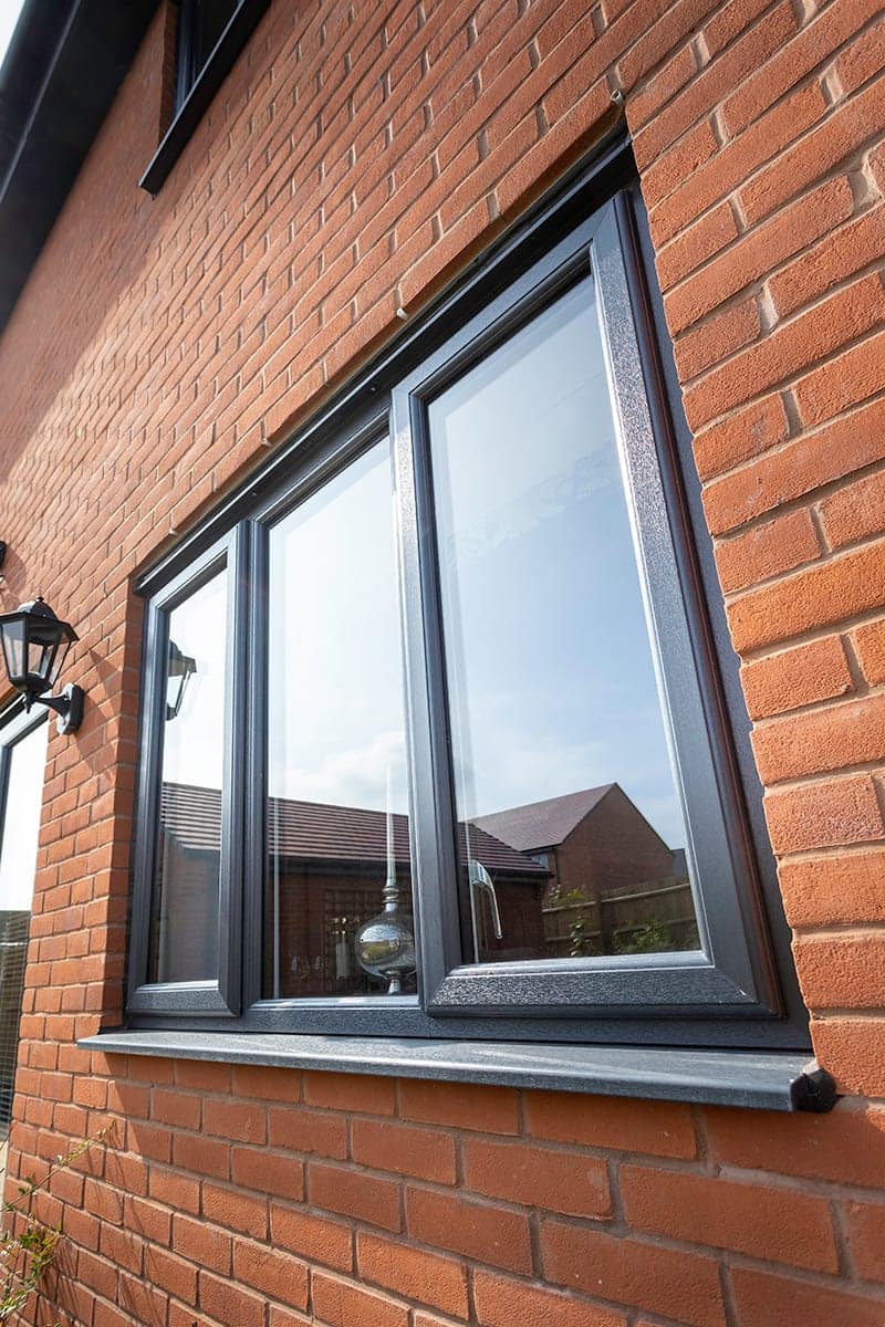 Anthracite-grey aluminium window on a brick house