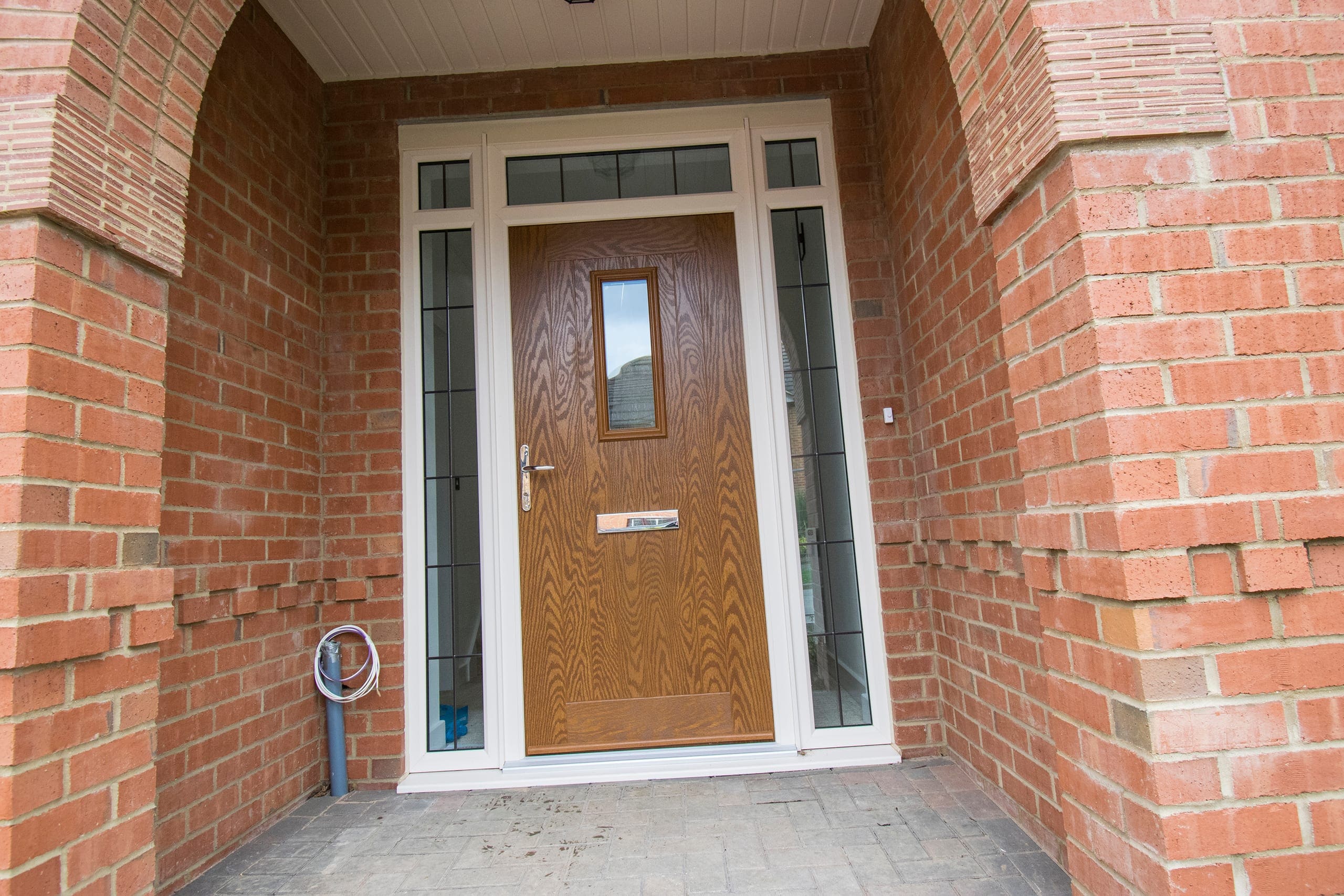 Oak-effect composite front door in a brick archway