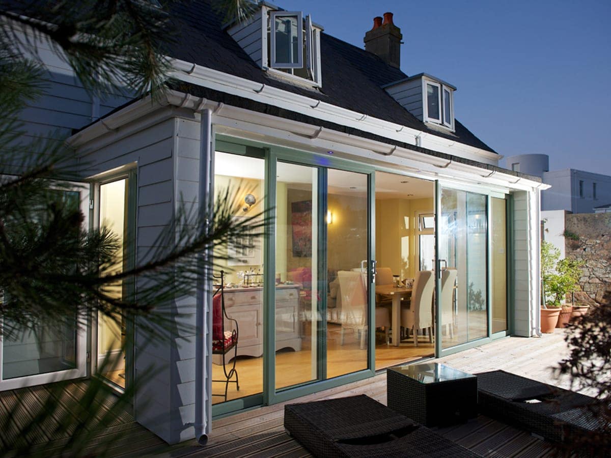 Grey aluminium bi-fold doors open onto a decked garden at dusk