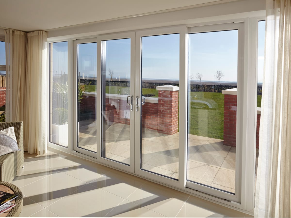 White bi-fold doors along a garden room overlooking open fields