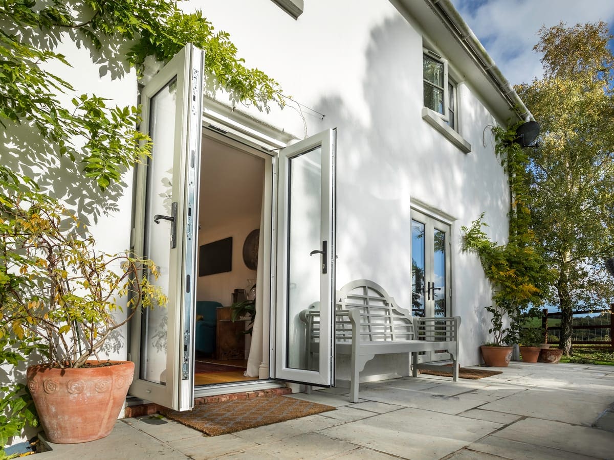 White bi-fold doors folded fully open onto a patio