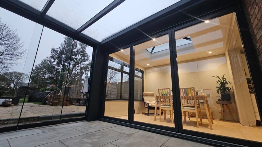 Anthracite-framed glazing and doors seen from inside a bright garden room