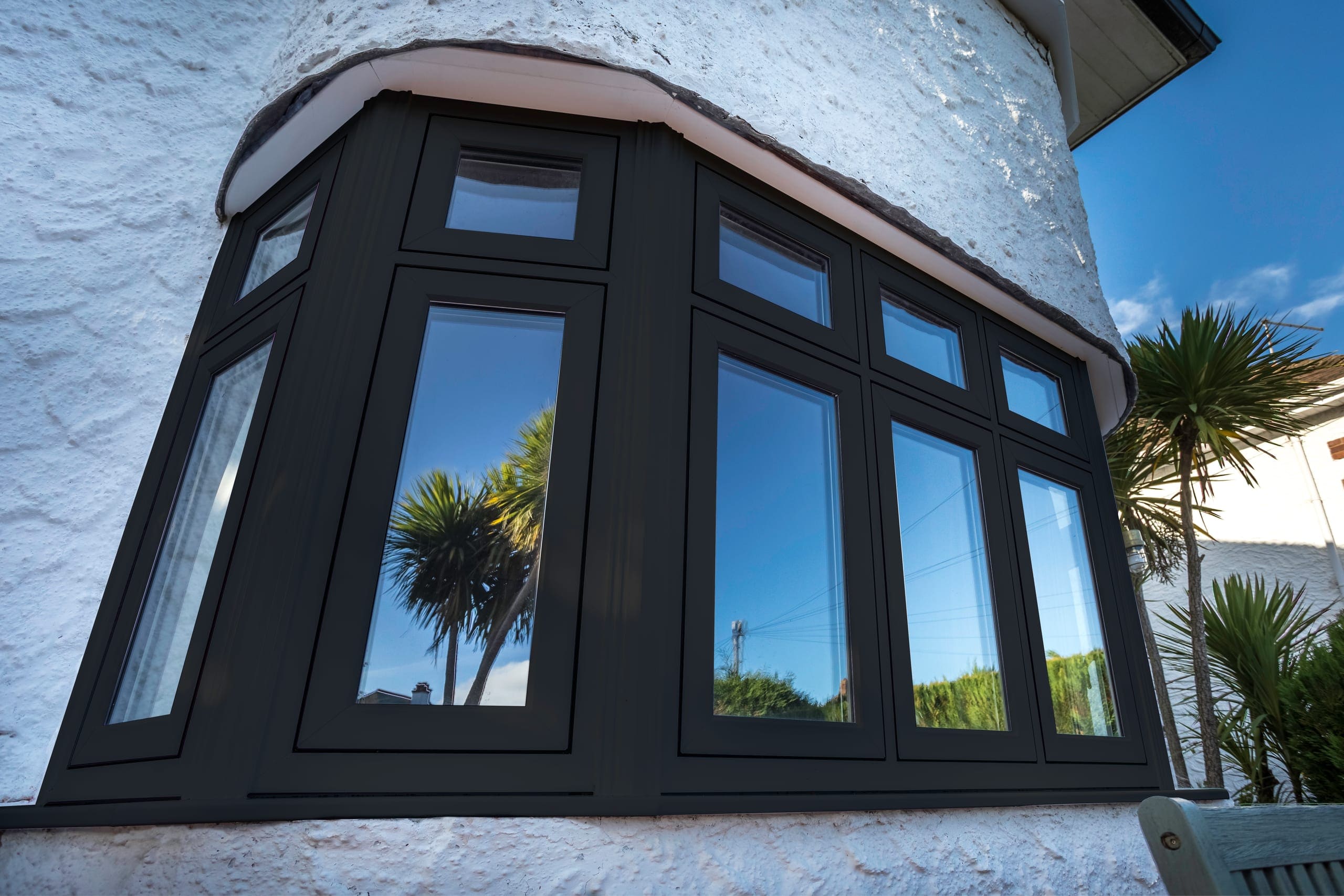 Anthracite-grey aluminium bay window on a rendered house