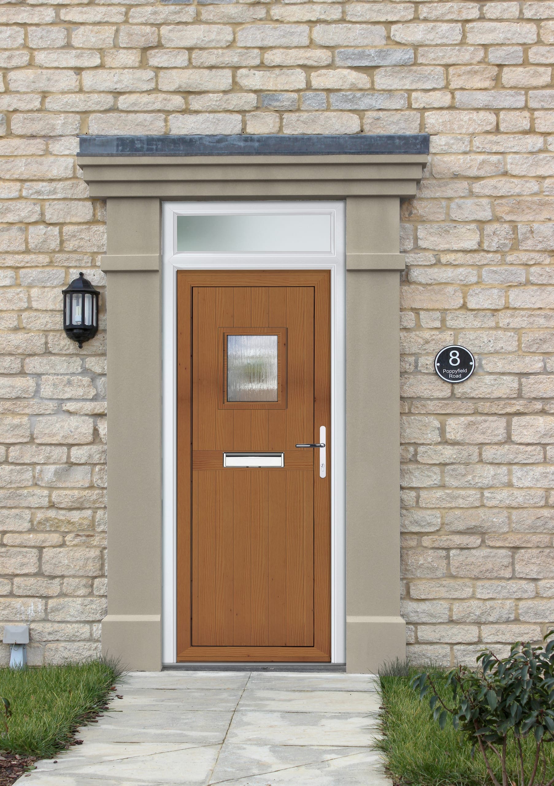 Oak-effect composite front door on a stone house