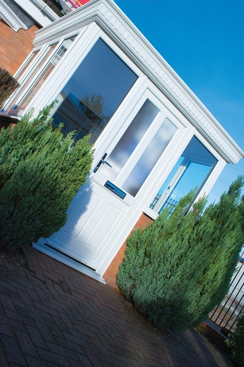 White uPVC front door framed by conifers
