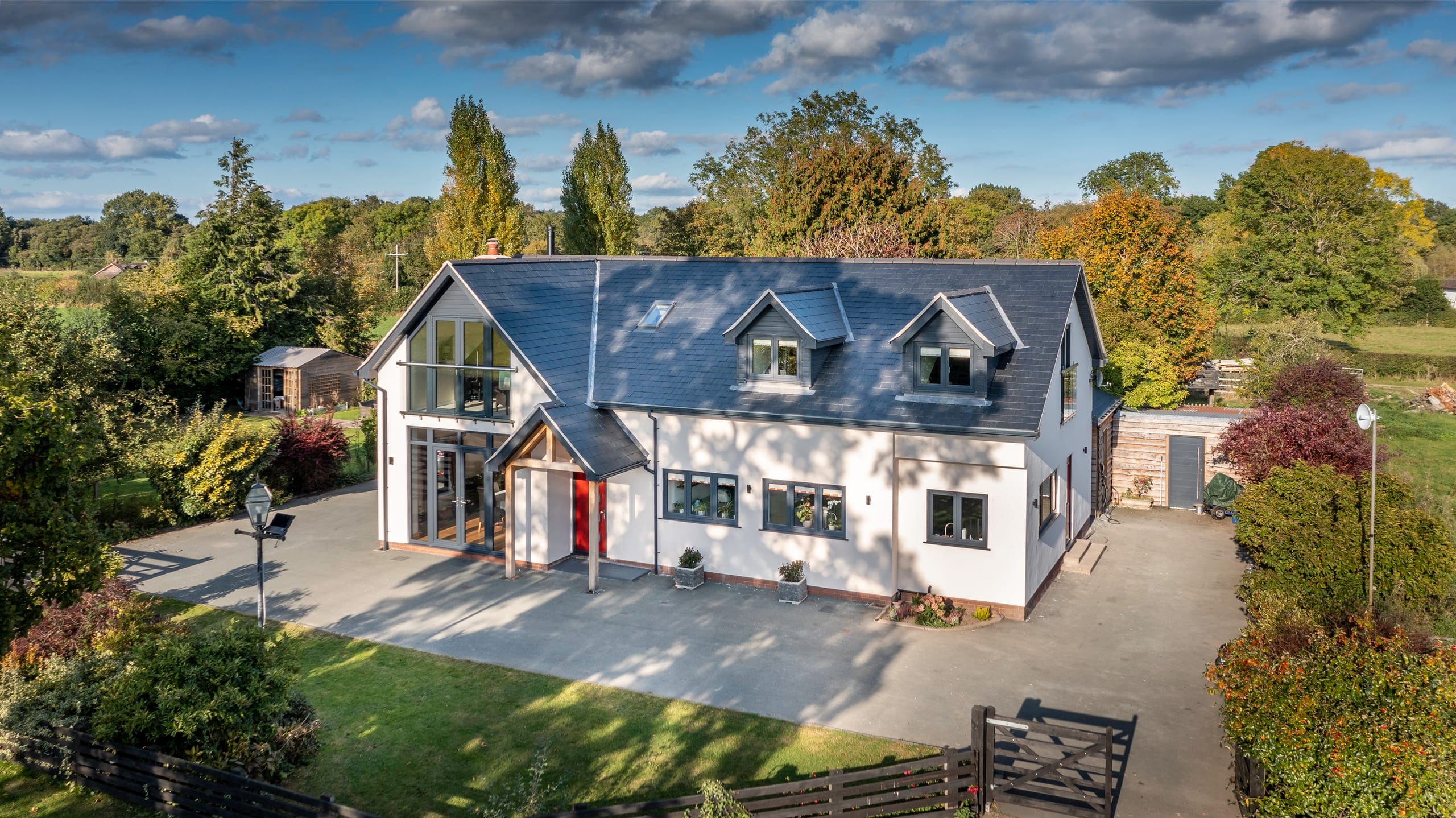 White rendered home with full-height gable glazing seen from above
