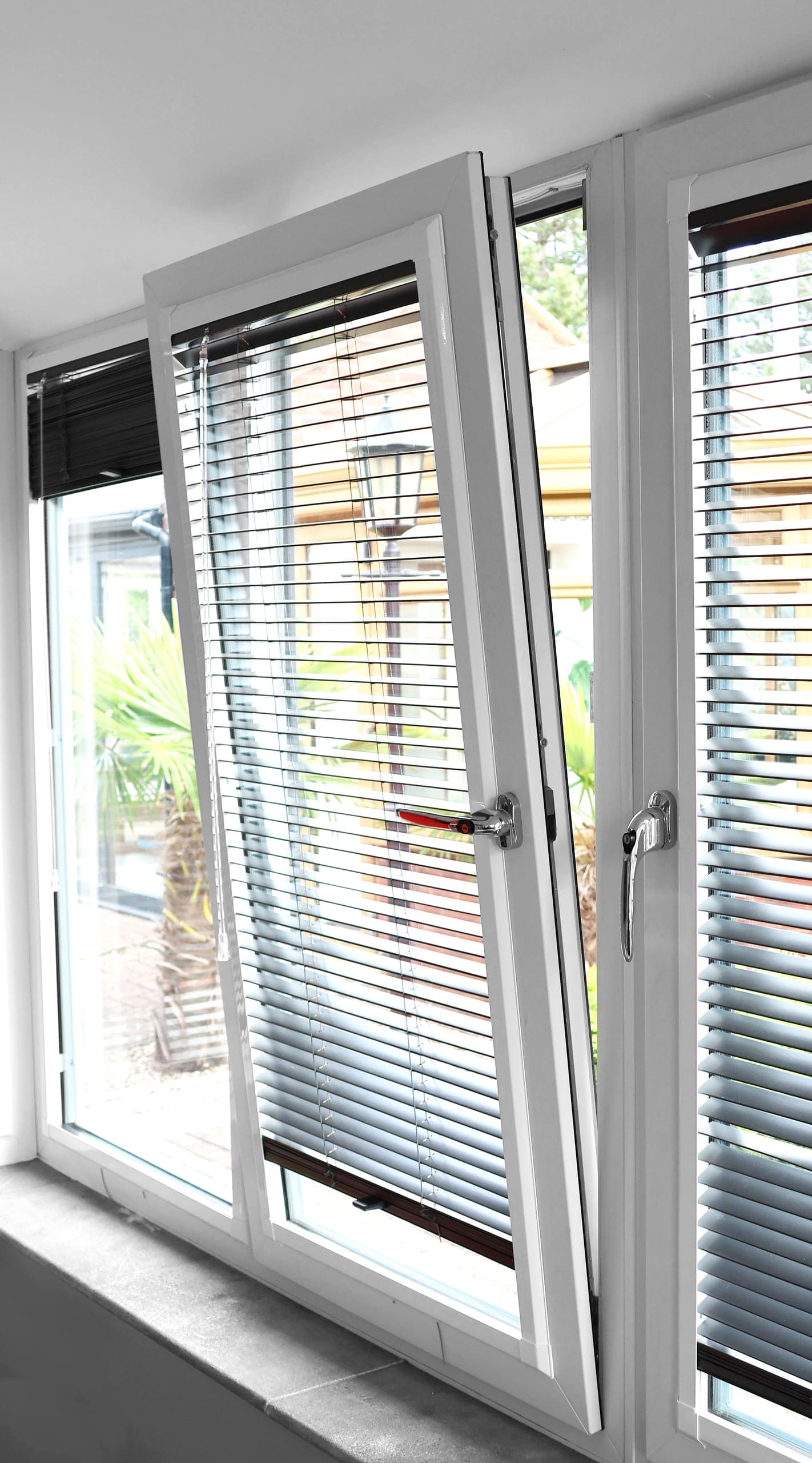 White uPVC window tilted open at the top with internal blinds